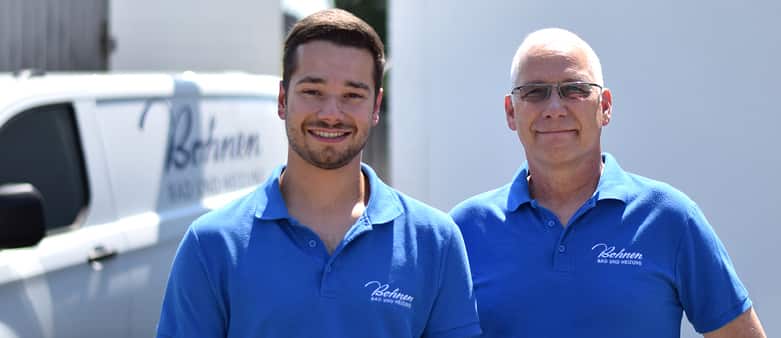 Vater und Sohn – Stefan und Martin Bohnen in blauen Firmenpolos vor ihrem Handwerksbetrieb
